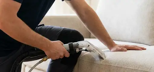 Professional upholstery cleaner deep-cleaning a fabric sofa with a handheld extraction tool, Jacksonville, FL.